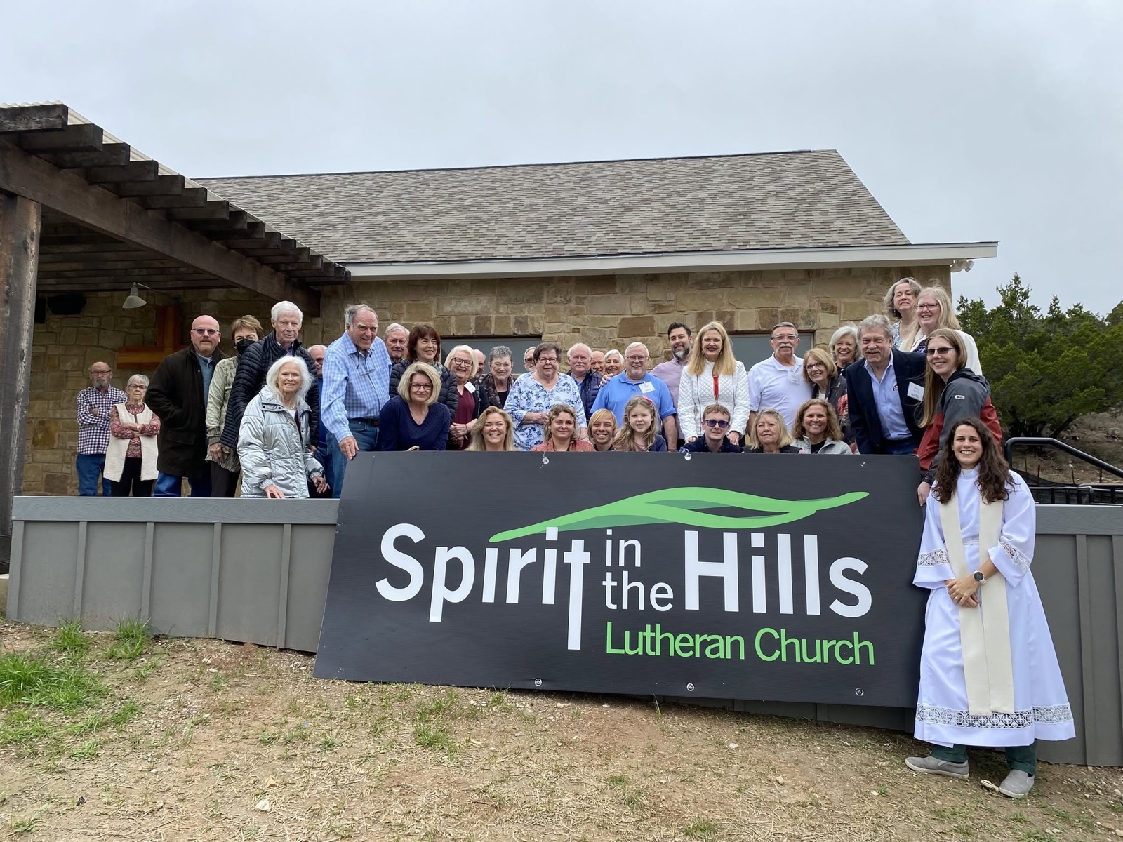 The whole congregation gathered outside the church behind the Spirit in the Hills road sign, with the pastor standing alongside.
